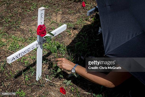 Woman places roses at the cross of a loved one at the mass grave on the grounds of the Holy Cross Memorial Garden on November 8, 2014 in Tacloban,...