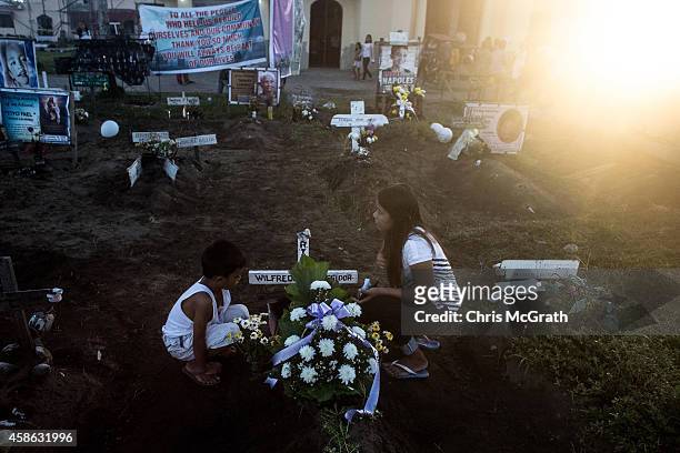 Family members sit at the grave of a loved one at the mass grave site at San Joaquin church on November 8, 2014 in Tacloban, Leyte, Philippines....
