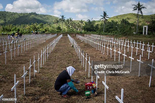 Woman sits at the cross of a loved one at the mass grave on the grounds of the Holy Cross Memorial Garden on November 8, 2014 in Tacloban, Leyte,...