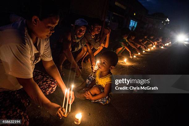 People sit around candles on the roadside in San Jose during the candlelight memorial on November 8, 2014 in Tacloban, Leyte, Philippines. People...