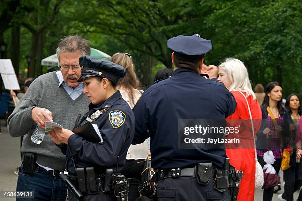 nypd female officer helps person with directions, central park, nyc - gun holster stock pictures, royalty-free photos & images