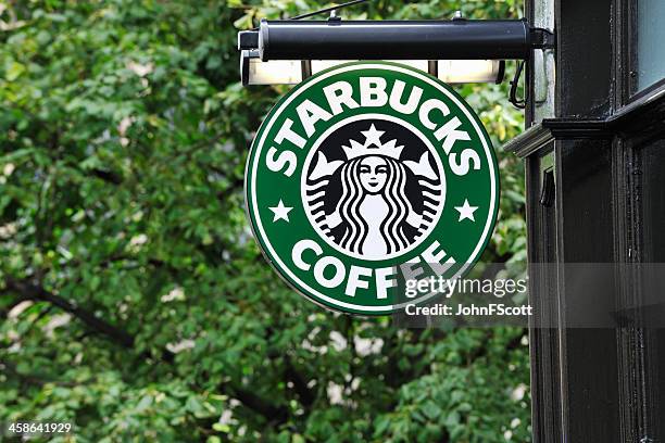 starbucks coffee sign hanging outside a shop - starbucks stockfoto's en -beelden