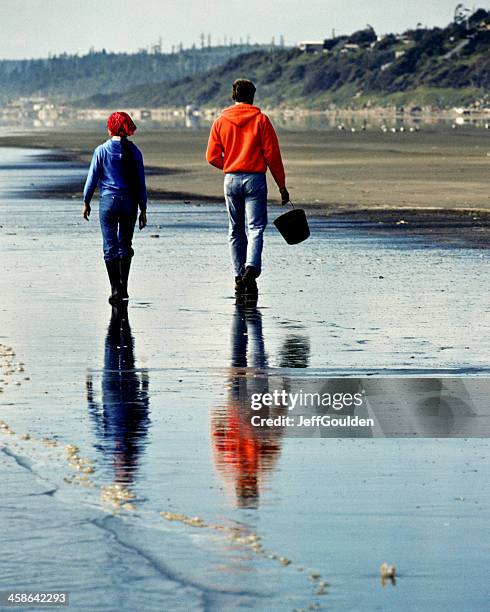 young couple walking on beach is reflected in wet sand - olympic peninsula stock pictures, royalty-free photos & images