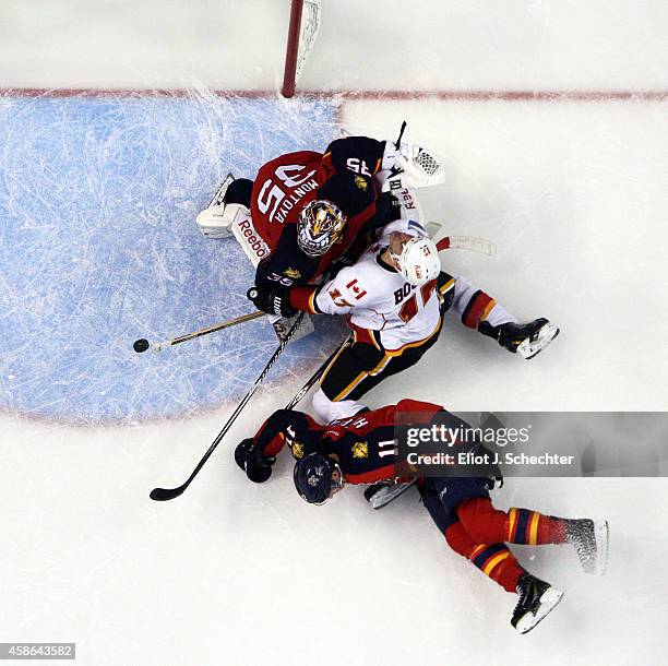 Lance Bouma of the Calgary Flames collides with Goaltender Al Montoya of the Florida Panthers and teammate Jonathan Huberdeau at the BB&T Center on...