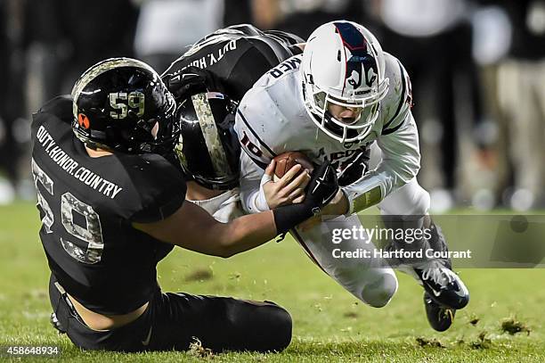 Army defenders Jon Voit and Jeremy Timpf bring down UConn quarterback Chandler Whitmer on a 13-yard rush that put UConn on the Army's 13-yard on...