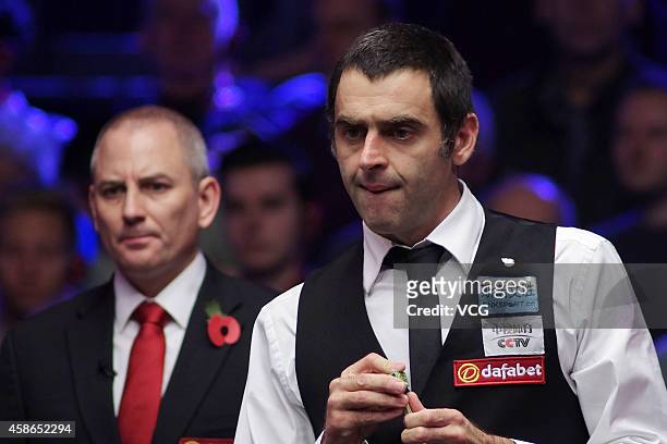 Ronnie O'Sullivan of England chalks his cue against Ding Junhui of China on day five of the 2014 Dafabet Champion of Champions at The Ricoh Arena on...