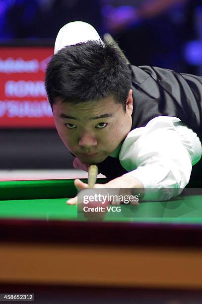 Ding Junhui of China plays a shot against Ronnie O'Sullivan of England on day five of the 2014 Dafabet Champion of Champions at The Ricoh Arena on...