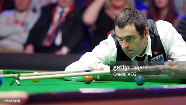 Ronnie O'Sullivan of England plays a shot against Ding Junhui of China on day five of the 2014 Dafabet Champion of Champions at The Ricoh Arena on...