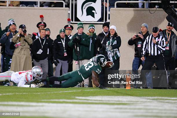 Jeremy Langford of the Michigan State Spartans tackled by Tyvis Powell of the Ohio State Buckeyes against the Ohio State Buckeyes at Spartan Stadium...