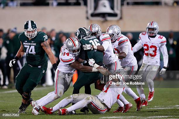 Group of Ohio State Buckeyes defenders tackle Aaron Burbridge of the Michigan State Spartans in the second half of the game at Spartan Stadium on...