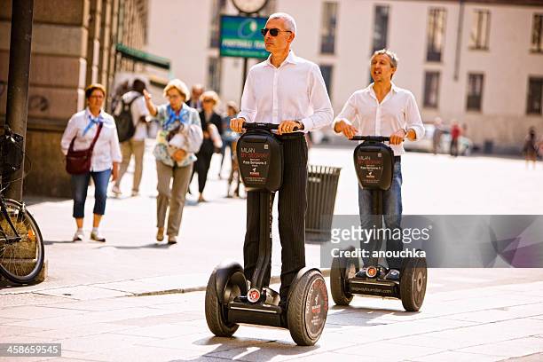 two men riding segway through piazza del duomo, milan, italy - segway stockfoto's en -beelden