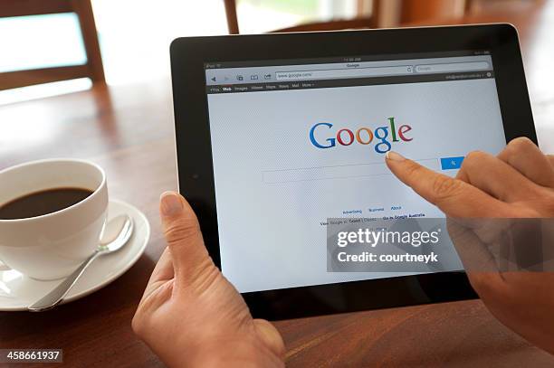 mano femmina che tiene un ipad con google. - google brand name foto e immagini stock