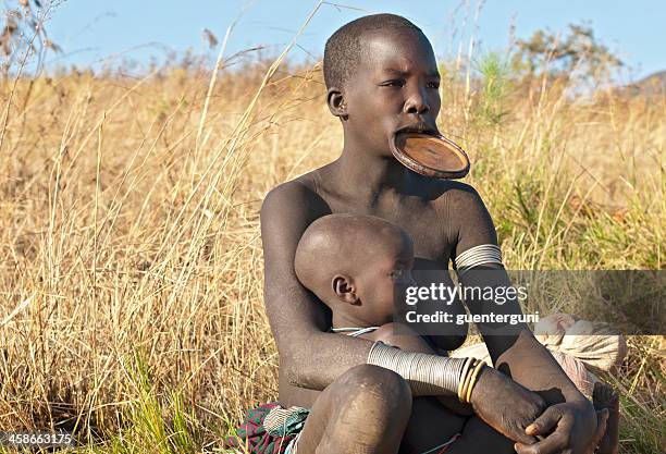 surma frau mit lip plate tragen ihr baby, süd-äthiopien - body piercings stock-fotos und bilder