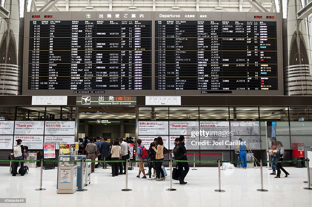Departure board and passengers at Narita airport