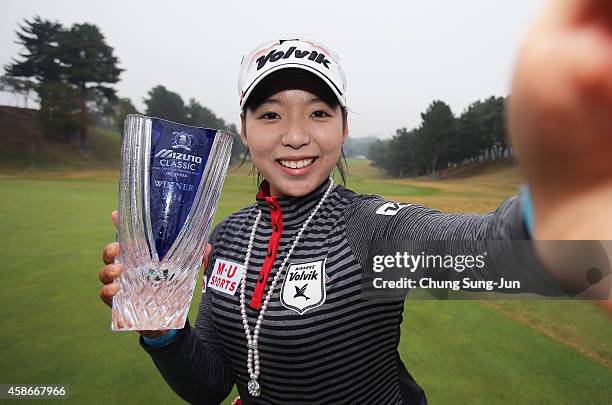 Mi-Hyang Lee of South Korea imitates a 'selfie' as she poses with the trophy during a ceremony following the Mizuno Classic at Kintetsu Kashikojima...