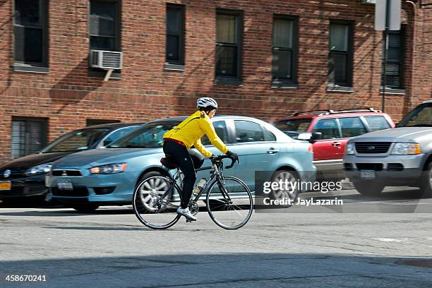female bicyclist approaching bike lane, upper manhattan, nyc - next to stock pictures, royalty-free photos & images