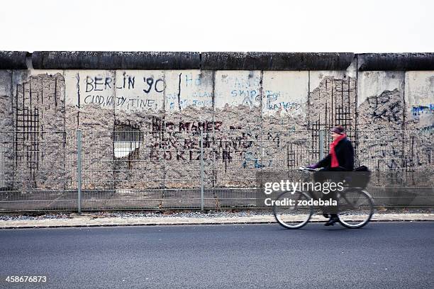 man cycling in front of berlin wall, east side, germany - the berlin wall stock pictures, royalty-free photos & images