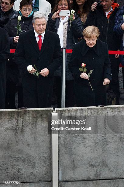German Chancellor Angela Merkel , Berlin's Major Klaus Wowereit and other dignitaries place flowers in between slats of the former Berlin Wall at the...