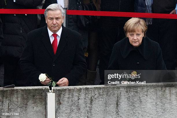 German Chancellor Angela Merkel , Berlin's Major Klaus Wowereit and other dignitaries place flowers in between slats of the former Berlin Wall at the...