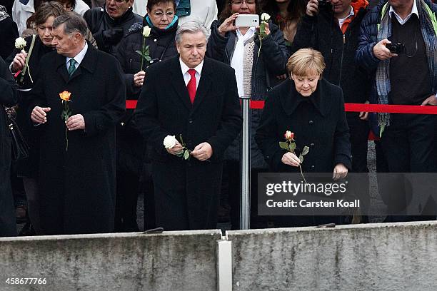 German Chancellor Angela Merkel , Berlin's Major Klaus Wowereit and other dignitaries place flowers in between slats of the former Berlin Wall at the...