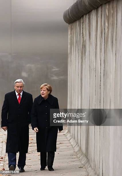 Berlin Mayor Klaus Wowereit and German Chancellor Angela Merkel walk along a section of the former Berlin Wall during celebrations for the 25th...