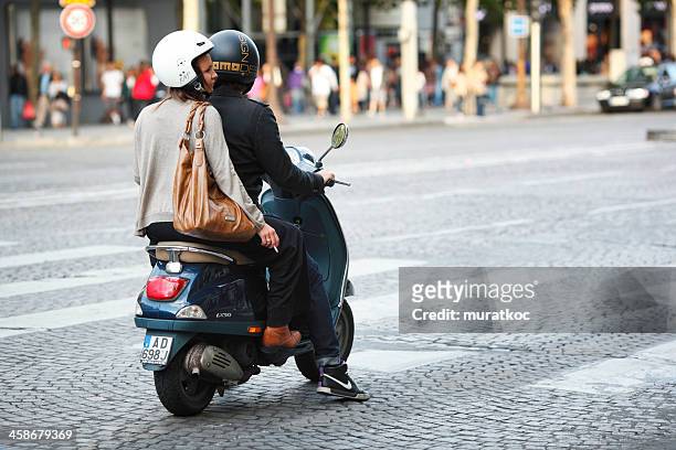 young couple riding scooter in champs elysees - vespa stockfoto's en -beelden