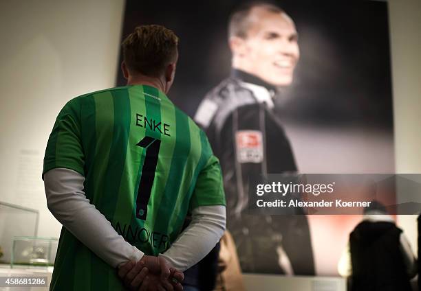 Fan of goalkeeper Robert Enke, wearing a soccer jersey of Enke, stands in front of a large billboard at the special exhibition "ROBERT gedENKEn" at...