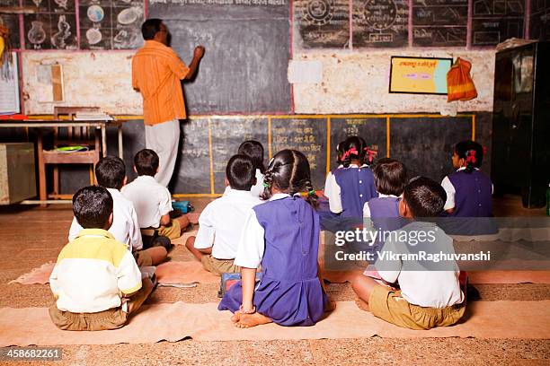 male teacher teaching students in a rural school of india - two female teachers blackboard stockfoto's en -beelden