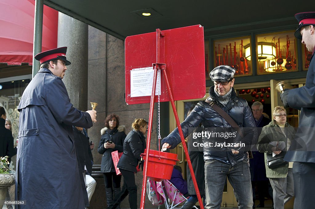 Man donating to Slavation Army Christmas bucket at Macy's, NYC