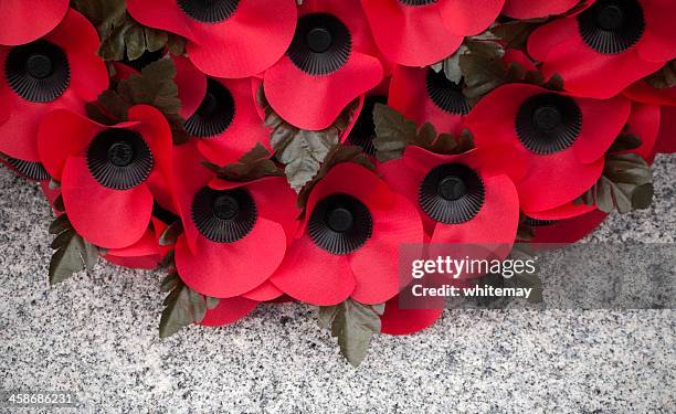 poppy wreath on a stone war memorial - remembrance day stock pictures, royalty-free photos & images