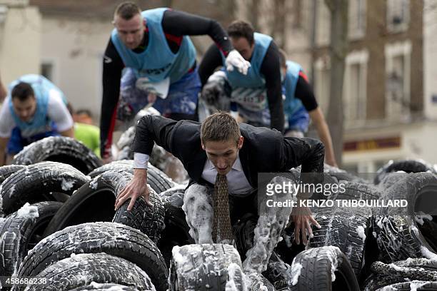 Participants covered in foam climb over tyres as they compete in the "Fishermans Friend StrongmanRun", a 24-kilometre obstacle course, in...