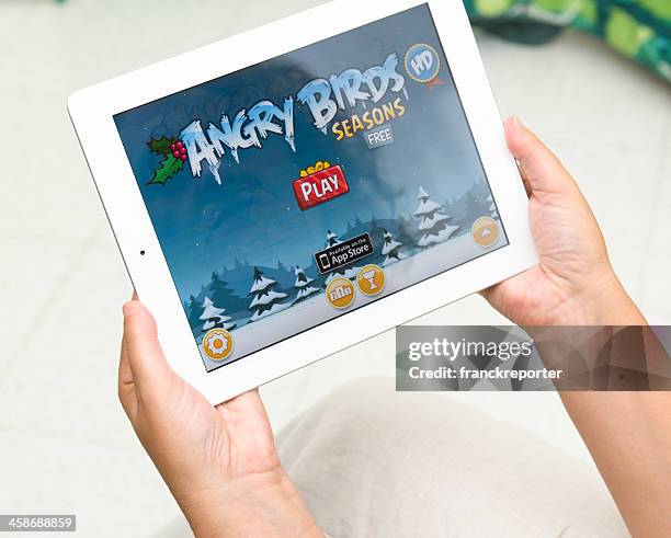 woman holding a digital tablet and playing angry birds season. - angry birds namngivna videospel bildbanksfoton och bilder