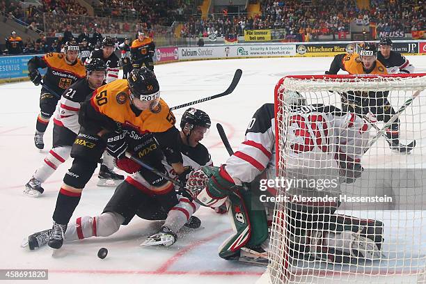 Patrick Hager of Germany skates with Chris Abbott of Canada and his goalie Chris Mason during match 6 of the Deutschland Cup 2014 between Canada and...