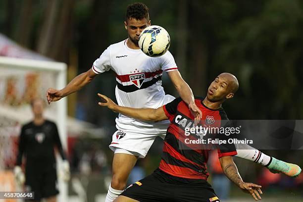 Lucao of Sao Paulo battles for the ball with Dinei of Vitoris during the match between Vitoria and Sao Paulo as part of Brasileirao Series A 2014 at...