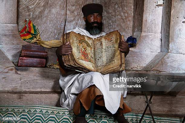 coptic priest with old bible - coptic christians stockfoto's en -beelden