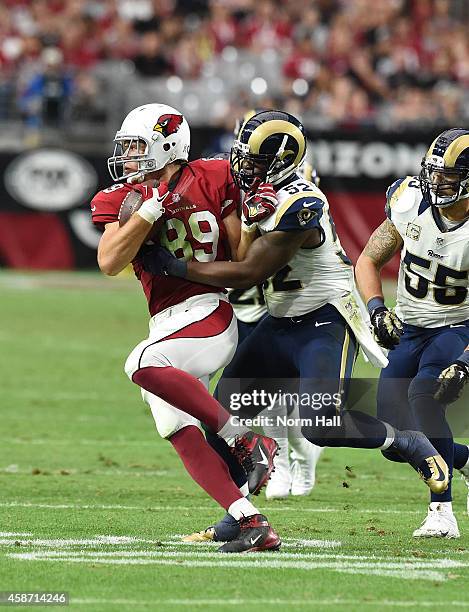 Tight end John Carlson of the Arizona Cardinals runs with the football under pressure from outside linebacker Alec Ogletree of the St. Louis Rams in...