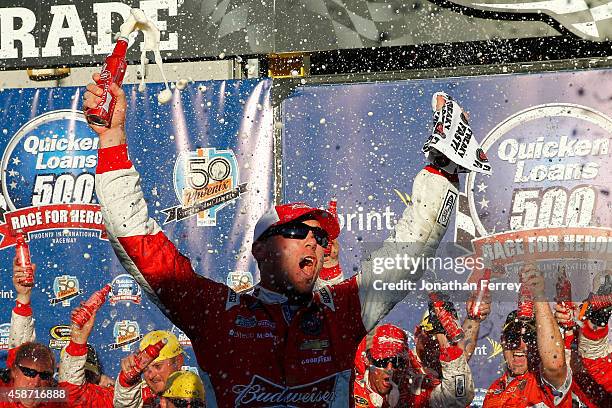 Kevin Harvick, driver of the Budweiser Chevrolet, celebrates in victory lane after winning the NASCAR Sprint Cup Series Quicken Loans Race for Heroes...