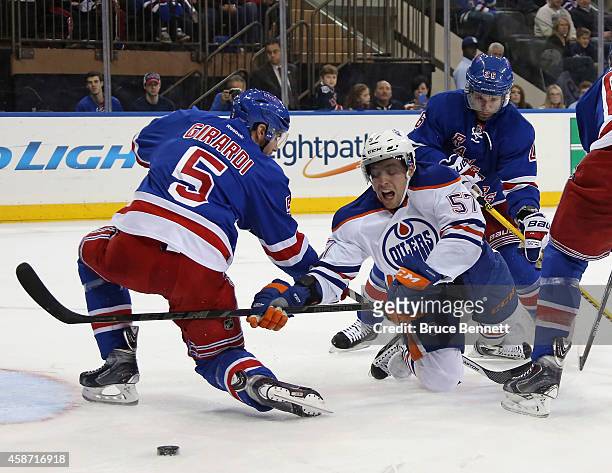 Dan Girardi and Martin St. Louis of the New York Rangers defend against David Perron of the Edmonton Oilers during the first period at Madison Square...