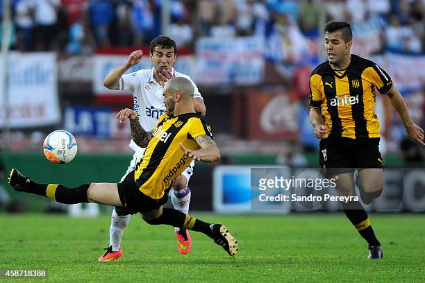Damián Macaluso and Diego Silvestre of Peñarol fight for the ball with Sebastián Fernández of Nacional during a match between Nacional and Peñarol as...