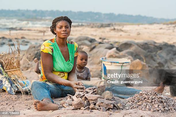 woman with children is crushing stones for a living - democratische republiek congo stockfoto's en -beelden