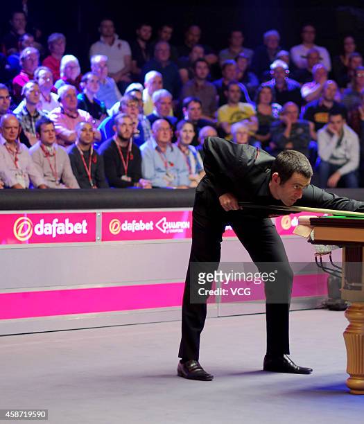 Ronnie O'Sullivan of England plays a shot against Judd Trump of England during their final match on day six of the 2014 Dafabet Champion of Champions...