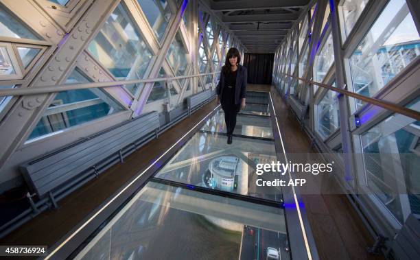 Woman walks across a glass viewing platform on the high-level Walkways to launch the new viewing experience at the Tower Bridge Exhibition centre in...