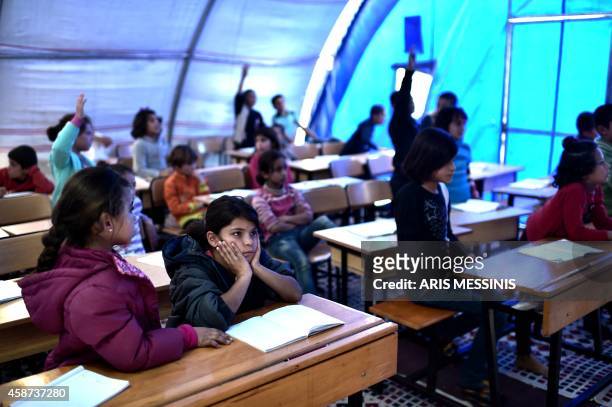 Syrian Kurdish children take lessons on November 10, 2014 in a makeshift school tent in a refugee camp in the town of Suruc, Sanliurfa province....