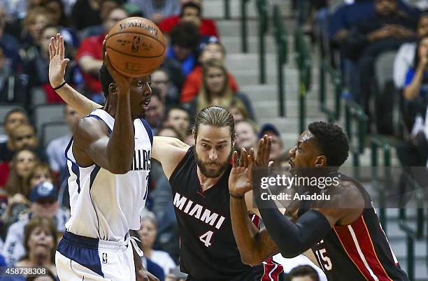 Al-Farouq Aminu of Dallas Mavericks in action against Josh McRoberts and Mario Chalmers of Miami Heat during the NBA basketball game between Miami...