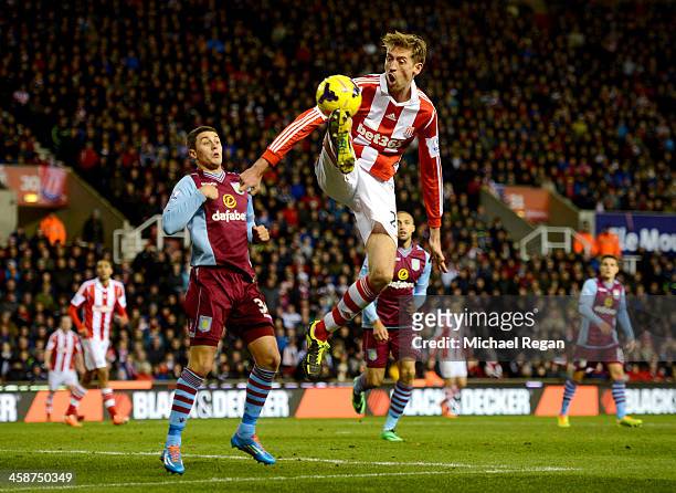 Peter Crouch of Stoke City controls the ball from Matthew Lowton of Aston Villa during the Barclays Premier League match between Stoke City and Aston...