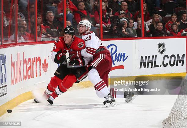 Oliver Ekman-Larsson of the Phoenix Coyotes squeezes Chris Neil of the Ottawa Senators along the boards at Canadian Tire Centre on December 21, 2013...