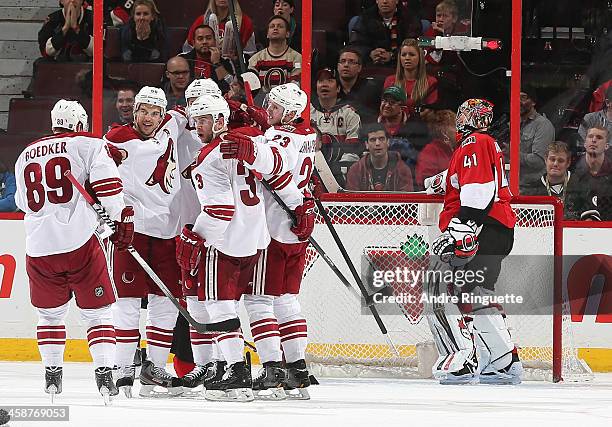 Craig Anderson of the Ottawa Senators looks on as Antoine Vermette of the Phoenix Coyotes celebrates his second goal of the game with teammates...