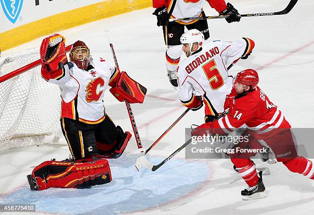 Jonas Hiller of the Calgary Flames reaches up to block a shot from Nathan Gerbe of the Carolina Hurricanes during their NHL game at PNC Arena on...