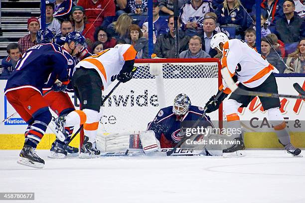 Curtis McElhinney of the Columbus Blue Jackets stops a shot from Wayne Simmonds of the Philadelphia Flyers as Scott Hartnell of the Philadelphia...