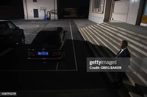 Chinese security official watches over cars parked on a basketball court in the Zhongnanhai leadership compound, while US President Barack Obama has...